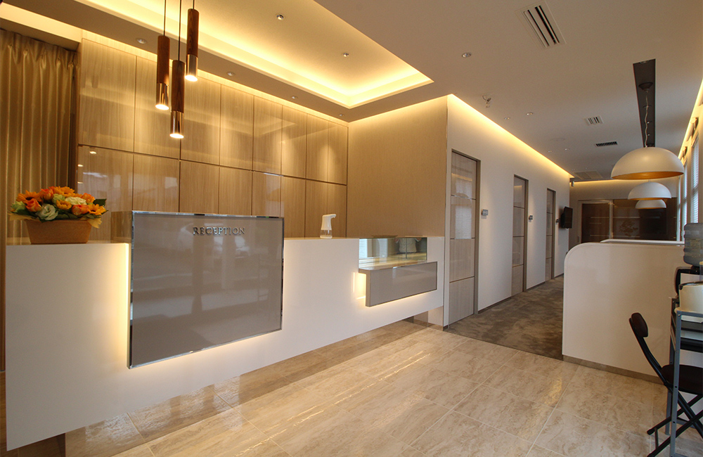 鴻巣市の漆原歯科・矯正歯科クリニックの、間接照明が美しい洗練された受付カウンター