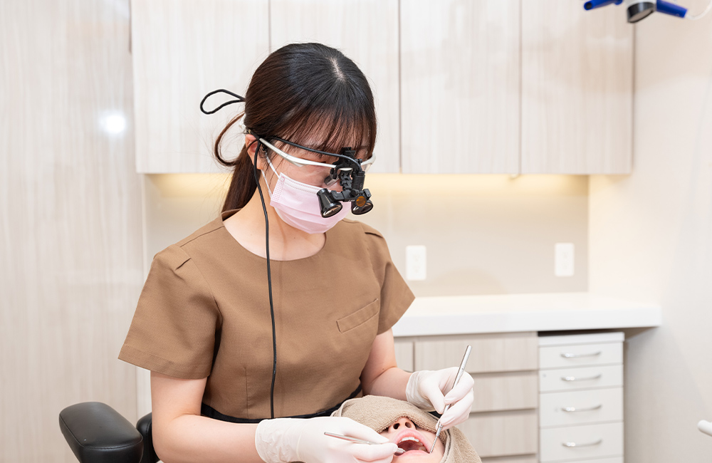 ルーペ（拡大鏡）を使用して精密なクリーニングを行う歯科衛生士